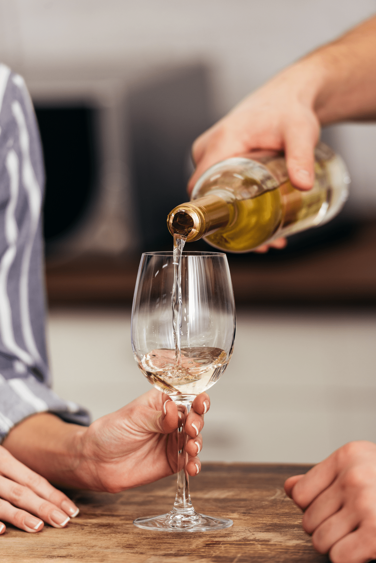 woman holding a glass of wine, man pouring an Australian vegan white wine