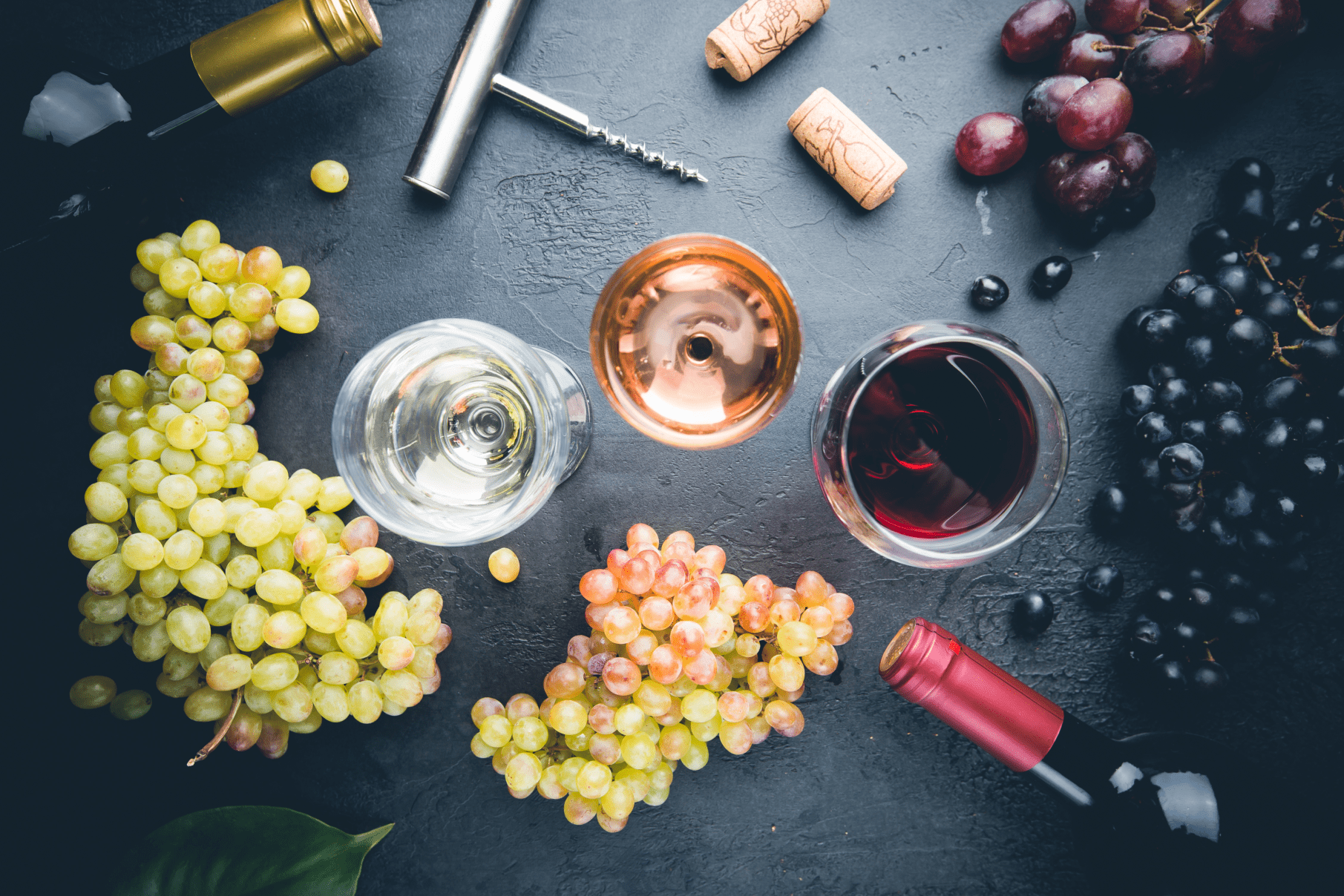 glass of vegan white, pink and red wine with grapes