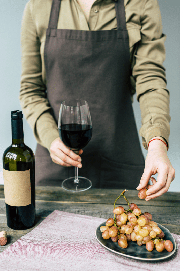 red vegan wine tasting, hand of person taking a grape